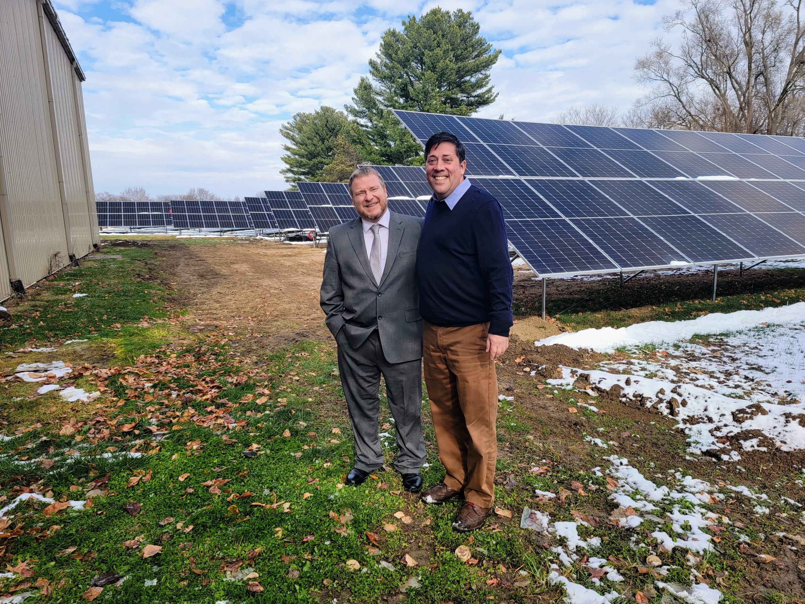 2 men smiling in front of solar equipment