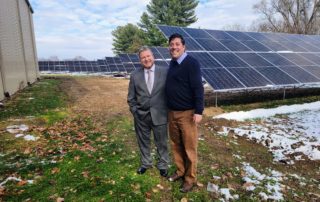 2 men smiling in front of solar equipment